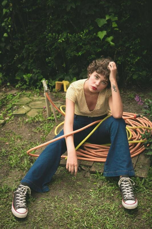 Woman sitting on a coiled garden hose in the garden